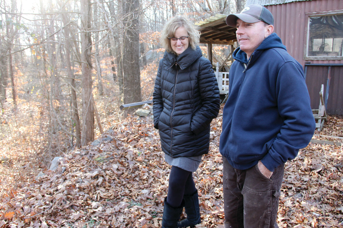 WOODS NOW: Carol and Carl Swanson look out on the wooded property of their neighbor. If the land becomes the site of Cranston’s newest solar farm, it will be clear-cut for arrays of solar panels.